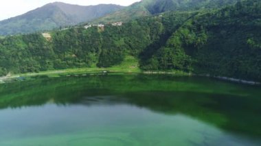 Telaga Menjer, Wonosobo 'nun nefes kesici hava manzarası. Etrafı yemyeşil ormanlarla, çay tarlalarıyla çevrili sakin bir göl ve yuvarlanan tepelerin arasına yerleşmiş dağınık konaklama yerleri sergiliyor..