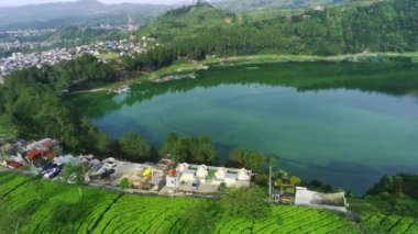 Telaga Menjer, Wonosobo 'nun nefes kesici hava manzarası. Etrafı yemyeşil ormanlarla, çay tarlalarıyla çevrili sakin bir göl ve yuvarlanan tepelerin arasına yerleşmiş dağınık konaklama yerleri sergiliyor..