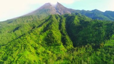 Merapi Dağı 'nın görkemli manzarası, Endonezya' nın merkezindeki aktif bir volkan. Zirvesinden yükselen duman gücünü ve güzelliğini gözler önüne seriyor. Yemyeşil bitki örtüsü yamaçları kaplıyor.