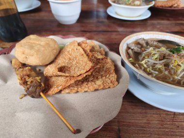 Bir kase çorba, bir tabak kızarmış tempeh, bir şişe satay ve kızarmış bir top..