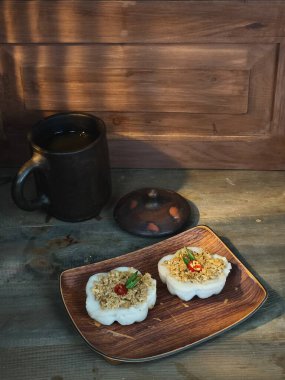 Two servings of kue talam, a traditional Indonesian steamed cake, are beautifully displayed on a wooden plate. The cakes are topped with a savory topping clipart