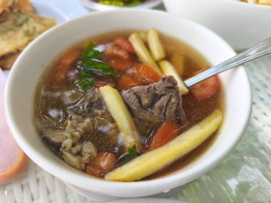 Bir kase lezzetli görünümlü çorba, et, patates ve sebze parçaları..