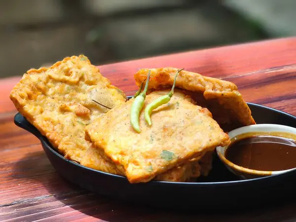 Altın sarısı Tempe Mendoan, soya fasulyesinden yapılan çıtır bir Endonezya aperatifi, baharatlı sosla servis edilir..