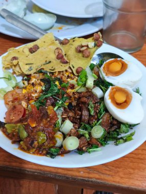 Canlı bir tabak Nasi Campur, lezzetli pilav, tuzlu yumurta, çıtır kraker ve bir dizi aromalı meze içeren Endonezya yemeği..