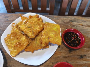 Altın sarısı Tempe Mendoan, soya fasulyesinden yapılan çıtır bir Endonezya aperatifi, baharatlı sosla servis edilir..