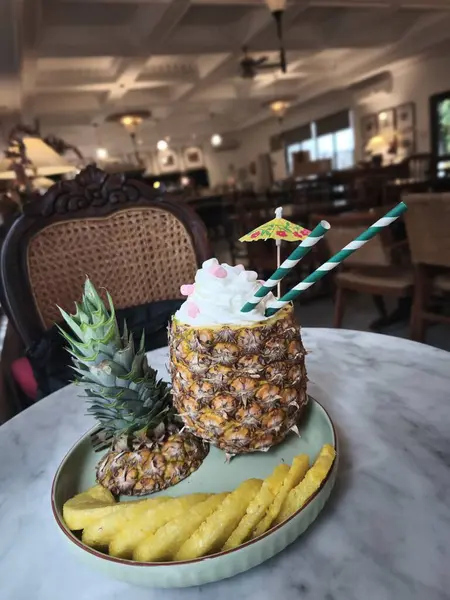 Krem şanti ve renkli bir şemsiyeyle doldurulmuş içi boş bir ananasla servis edilen ferahlatıcı bir ananas kokteyli. Bir Pinacolada.