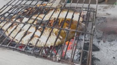 Situbondo, Doğu Java, Endonezya 'daki metal barlardan yapılmış derme çatma bir ızgarada bütün bir balık ızgara ediliyor..