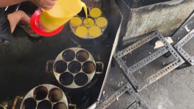 Geleneksel bir Endonezya yemeği olan Kue Lumpur Sidoarjo 'yu pişirmek için hamuru kalıplara döken bir sokak satıcısı. Altın hamuru sıcak bir yüzeyde yuvarlak kalıpları doldurur..