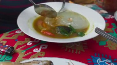 Papeda, Endonezya 'nın geleneksel sago lapası lezzetli sarı balık çorbasıyla servis edilir, otlar ve biberlerle süslenir..