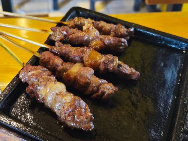 Baharatlı keçi eti şişi ya da sıcak bir tabakta satay yanında taze sebze ve sosla birlikte..