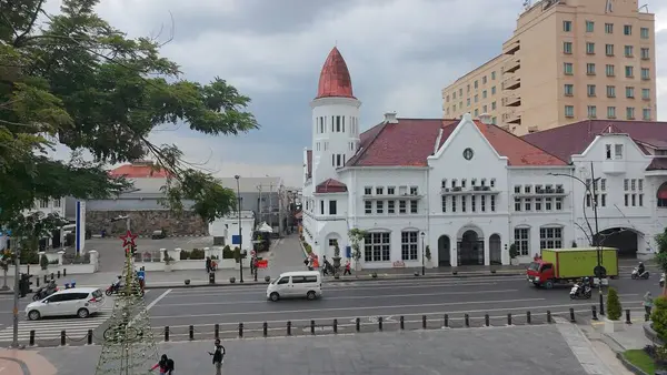 4 Ocak 2025. Surabaya, Endonezya 'da hareketli bir sokak sahnesi. Belirgin bir özellik, kendine özgü kırmızı kiremitli çatısı ve bir kulesi olan büyük bir sömürge dönemi binasıdır..