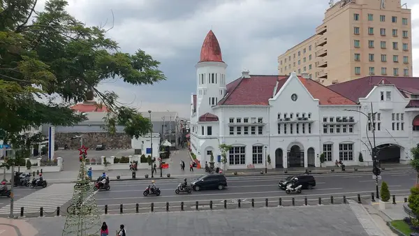 4 Ocak 2025. Surabaya, Endonezya 'da hareketli bir sokak sahnesi. Belirgin bir özellik, kendine özgü kırmızı kiremitli çatısı ve bir kulesi olan büyük bir sömürge dönemi binasıdır..