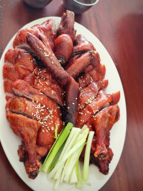 Çok güzel bir tabak Pekin ördeği. Ördek ustalıkla oyulmuş ve düzenlenmiş, zengin, kırmızımsı bir ciltten parlayan ve susam tohumları serpiştirilmiş..