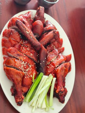 Çok güzel bir tabak Pekin ördeği. Ördek ustalıkla oyulmuş ve düzenlenmiş, zengin, kırmızımsı bir ciltten parlayan ve susam tohumları serpiştirilmiş..