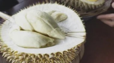 Durian satıcısı Durian 'ı alıcı için ikiye ayırıyor. Durianlar çok cazip görünüyor ve eti olgun ve sarı görünüyor..