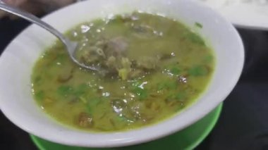 Cirebon, Endonezya 'dan geleneksel bir sığır çorbası olan empal gentong' un yakın plan görüntüsü, yemeden önce kaşıkla karıştırılıyor..
