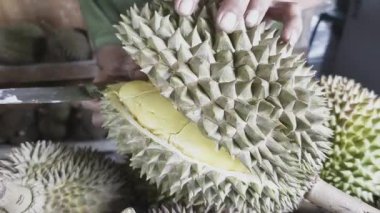 Durian satıcısı Durian 'ı alıcı için ikiye ayırıyor. Durianlar çok cazip görünüyor ve eti olgun ve sarı görünüyor..