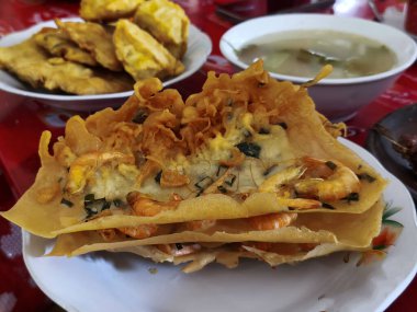 Lezzetli bir yığın Bakwan Udang veya Endonezya gevrek karides böreği bir kase çorba ve altın kızartma ile birlikte servis edilir..