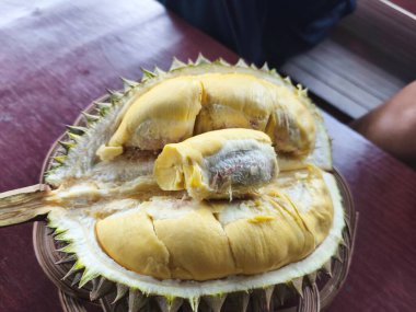 Lezzetli olgun bir Durian, kremsi sarı eti açıkta, tadını çıkarmaya hazır. Güçlü aroması ve zengin tadı ile bilinen eşsiz bir meyvedir.