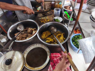 Bir satıcı empal gentong hazırlıyor, Endonezya usulü lezzetli bir et yemeği, zengin baharatlar ve taze malzemelerle. Duyular için bir ziyafet.