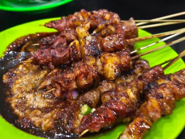 Succulent Sate Kambing skewers, grilled to perfection and served with a rich, savory sauce. A delightful treat for meat lovers clipart