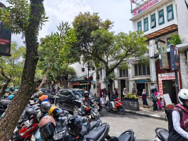 January 29, 2025. Bandung, Indonesia. A lively scene on Jalan Braga, bustling with traffic and pedestrians, featuring a colorful tour bus amidst the festive atmosphere of Chinese New Year celebrations clipart