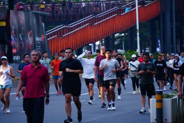 February 16, 2025. Jakarta, Indonesia. A vibrant scene from Car Free Day on Jalan Sudirman, showcasing diverse participants jogging and enjoying the fresh air in colorful athletic wear. clipart