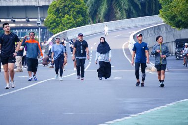 16 Şubat 2025. Jakarta, Endonezya. Jalan Sudirman 'ın Arabasız Günü' nden canlı bir sahne, çeşitli katılımcılar renkli atletizm kıyafetleriyle koşuyor ve temiz havanın tadını çıkarıyor..