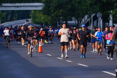 February 16, 2025. Jakarta, Indonesia. A vibrant scene from Car Free Day on Jalan Sudirman, showcasing diverse participants jogging and enjoying the fresh air in colorful athletic wear. clipart