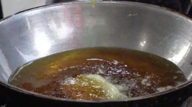 Tempe Mendoan 'ın yakın çekimi, Endonezya' nın geleneksel tempeh 'i, kızgın yağda kızartılıyor, köpüren ve cızırdayan dokular sergiliyor, hamur parçaları maşayla kaldırılıyor..