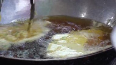 Tempe Mendoan 'ın yakın çekimi, Endonezya' nın geleneksel tempeh 'i, kızgın yağda kızartılıyor, köpüren ve cızırdayan dokular sergiliyor, hamur parçaları maşayla kaldırılıyor..