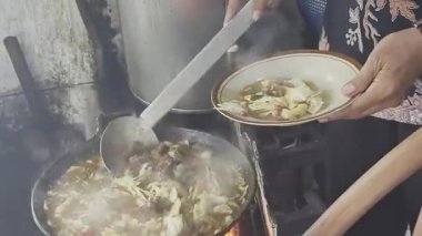 Tongseng satıcısı, Endonezya baharatlı keçi eti çorbası, büyük bir tavadan çorba dolduruyor, tabaktan buhar yükseliyor..