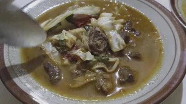 Bir tabak Tongseng, Endonezya baharatlı keçi eti çorbası, tadını çıkarmadan önce karıştırılıyor..