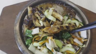 Japon yemeklerini karıştırmak için çubuk kullanan bir insanın yakın plan fotoğrafı. Teriyaki soslu ve sebzeli ızgara tavuk parçaları..