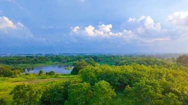 Bukit ular ya da Snake Hill, Batı Surabaya, Endonezya yakınlarındaki verimli bir arazinin havadan görünüşü, sakin bir su kütlesi, yeşillik ve uzaktaki modern binaları gösteriyor, doğayı kentsel yaşamla harmanlıyor.