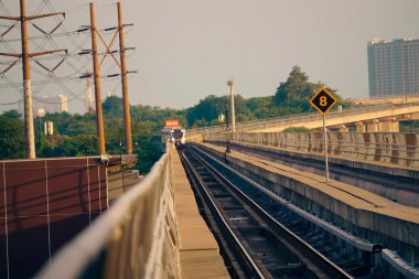 Modern bir LRT treni, Jakarta yakınlarında önemli bir hız limiti tabelasının yer aldığı şehir manzaralı yüksek bir pistte seyahat eder..