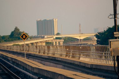 Modern bir LRT treni, Jakarta yakınlarında önemli bir hız limiti tabelasının yer aldığı şehir manzaralı yüksek bir pistte seyahat eder..