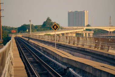Modern bir LRT treni, Jakarta yakınlarında önemli bir hız limiti tabelasının yer aldığı şehir manzaralı yüksek bir pistte seyahat eder..