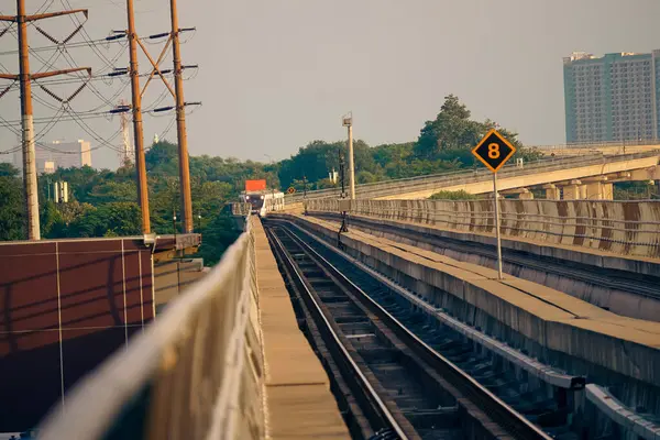 Modern bir LRT treni, Jakarta yakınlarında önemli bir hız limiti tabelasının yer aldığı şehir manzaralı yüksek bir pistte seyahat eder..