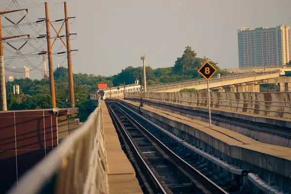 Modern bir LRT treni, Jakarta yakınlarında önemli bir hız limiti tabelasının yer aldığı şehir manzaralı yüksek bir pistte seyahat eder..