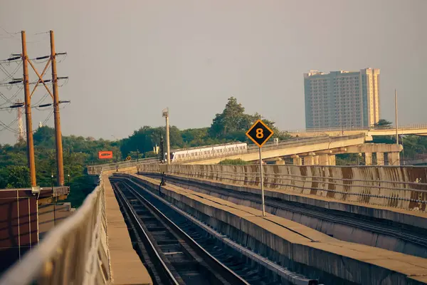Modern bir LRT treni, Jakarta yakınlarında önemli bir hız limiti tabelasının yer aldığı şehir manzaralı yüksek bir pistte seyahat eder..
