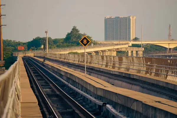 Modern bir LRT treni, Jakarta yakınlarında önemli bir hız limiti tabelasının yer aldığı şehir manzaralı yüksek bir pistte seyahat eder..