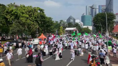 19 Nisan 2025. Surabaya, Endonezya. Kırmızı, beyaz, yeşil ve siyah bayraklar taşıyan kalabalık bir kalabalıkla Filistin Özgürlüğü için düzenlenen büyük şehir gösterisinin havadan görüntüsü. Hoparlörlerin ve ambulansların olduğu bir sahne.