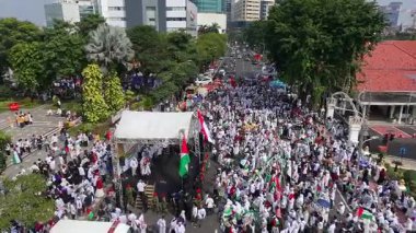 19 Nisan 2025. Surabaya, Endonezya. Kırmızı, beyaz, yeşil ve siyah bayraklar taşıyan kalabalık bir kalabalıkla Filistin Özgürlüğü için düzenlenen büyük şehir gösterisinin havadan görüntüsü. Hoparlörlerin ve ambulansların olduğu bir sahne.