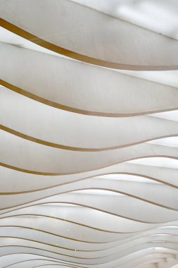 Dalgalı, katmanlı paneller dinamik, soyut bir kalıp yaratır, ışık ve gölgelerle oynar..