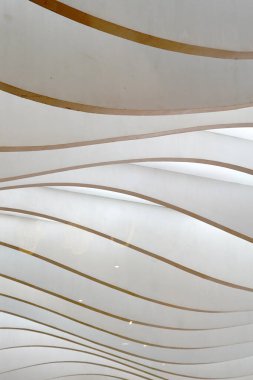 Dalgalı, katmanlı paneller dinamik, soyut bir kalıp yaratır, ışık ve gölgelerle oynar..