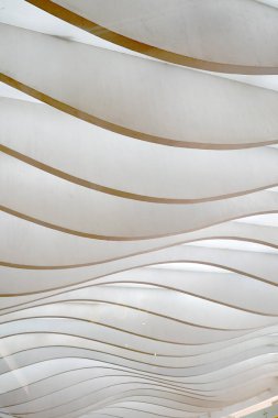 Dalgalı, katmanlı paneller dinamik, soyut bir kalıp yaratır, ışık ve gölgelerle oynar..