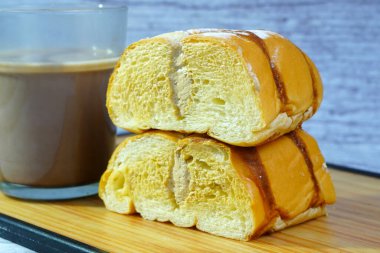 Çikolatalı ve pudra şekerli dilimlenmiş altın ekmeğin yanında bir kupa sütlü kahve kreması..