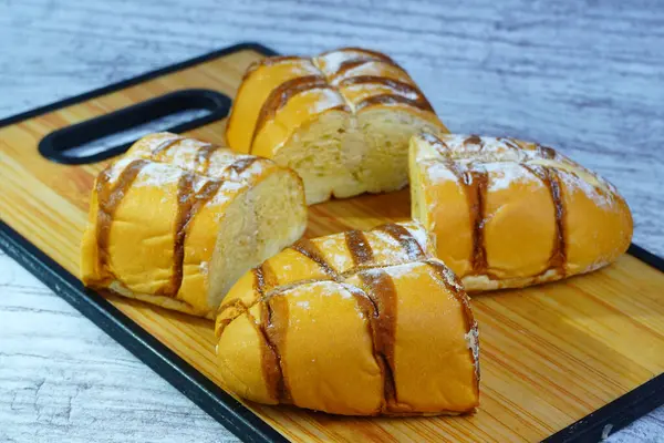 Çikolata serpiştirilmiş, ahşap bir tahtanın üzerine pudra şekeri serpiştirilmiş bir moka altın somunu parçaları..