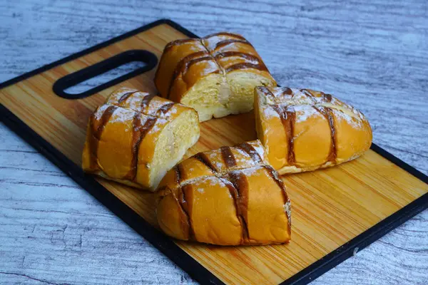 Çikolata serpiştirilmiş, ahşap bir tahtanın üzerine pudra şekeri serpiştirilmiş bir moka altın somunu parçaları..